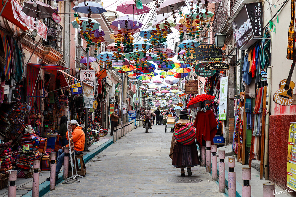 2 Bolivien La Paz  Hexenmarkt
Am Plaza San Francisco mit der gleichnamigen Kirche läuft man die angrenzende Straße Calle Santa Cruz hinauf. Nach nur wenigen Minuten erreicht man den "Mercado de Hechicería" (Markt der Zauberei) mit den bunten „Chiflerías“, den Läden der Hexen. Oft hängen an den Eingängen bestickte Tücher, Rucksäcke und andere Souvenirs. laut logistur.travel
Schlüsselwörter: La Paz